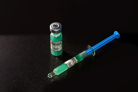 Concept that the vaccine is poison. Vial and syringe of vaccine with green liquid simulating that...