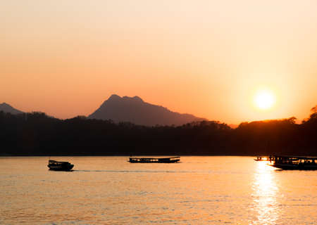 Boat fisherman silhouette at sunset on mekong riverの写真素材