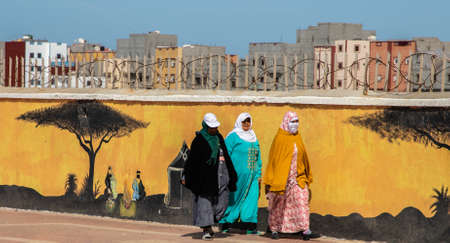 three women walking near the graffiti on the wall, Dakhla, Western Sahara, Moroccoのeditorial素材