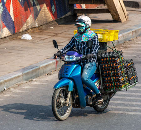 Vietnamese driving a motorbike and transporting a lot of packages. This is a typical Vietnam transport with motorcycle or scooterのeditorial素材