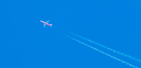 Air Berlin airplane flying at high altitude leaving its white wake over blue sky