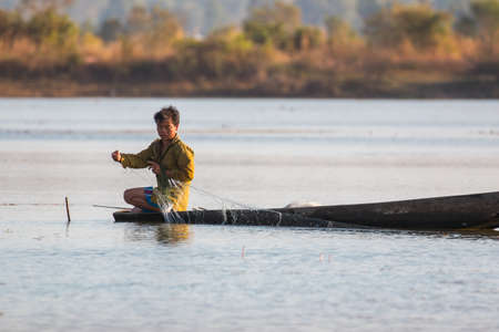 fisherman on canoe in tropical Bungva lake, Laoのeditorial素材