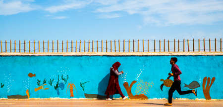 DAKHLA, MOROCCO, JAN 12, 2019: man and woman walking near the graffiti on the wall, Dakhla, Western Sahara, Moroccoのeditorial素材