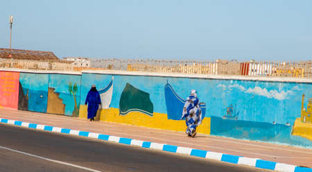 DAKHLA, MOROCCO, JAN 12, 2019: two women walking near the graffiti on the wall, Dakhla, Western Sahara, Moroccoのeditorial素材
