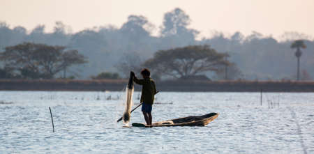 fisherman on canoe in tropical Bungva lake, Laosの写真素材