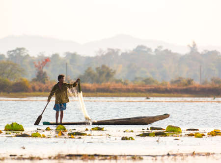 fisherman on canoe in tropical Bungva lake, Laosの写真素材