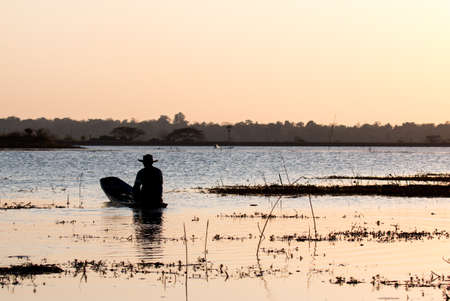 Fisherman on canoe in tropical Bungva lake, Laosの写真素材