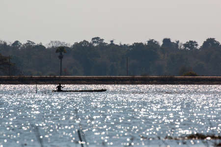 Fisherman on canoe in tropical Bungva lake, Laosの写真素材