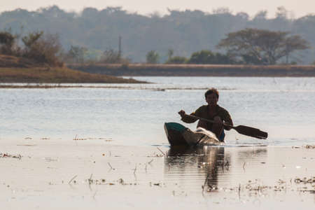 fisherman on canoe in tropical Bungva lake, Laosのeditorial素材