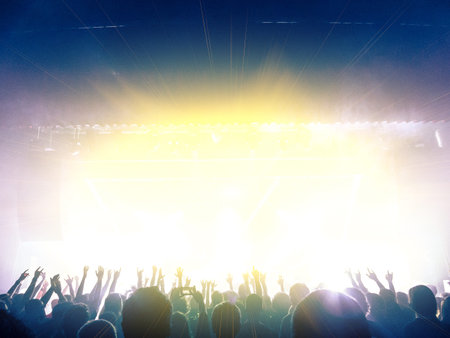 Concert hall crowded with festive clapping people in front of a big stageの写真素材