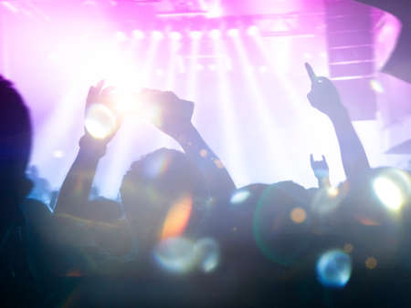 Front view of a concert stage with concert crowd silhouettes clapping and raising hands to the band showの写真素材
