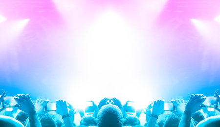 Front view of a concert stage with concert crowd silhouettes clapping and raising hands to the band...