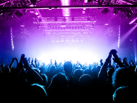 Concert hall with many concert attendants clapping in front of the stage
