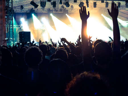Concert hall crowded with people in front of a stage lit for the gig.の写真素材