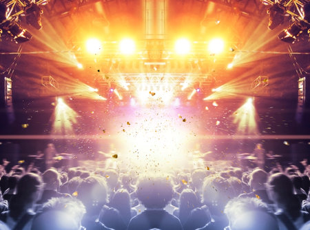 Concert spectators in front of a bright stage with live musicの写真素材