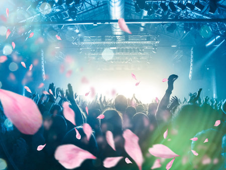 Image shot during a music festival. Light comes from a stage with a band show, people silhouettes...