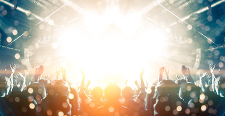 Front view of a concert stage with unrecognizable people silhouettes clapping and raising hands
