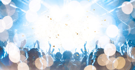 Front view of a concert stage with unrecognizable people silhouettes clapping and raising hands