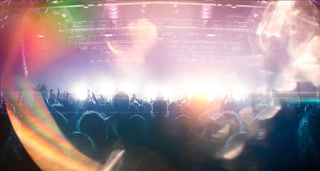 Concert crowd point of view inside a large concert hall during a music festival, the lit stage is visible.の写真素材