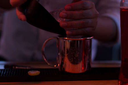Close up on a copper mug filled with a cocktail by the bartender, scene is a dark interior.のeditorial素材