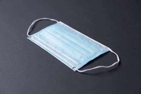 Close-up shot of a surgical respiratory mask against corona virus covid-19 infection, resting on a backdrop.の写真素材