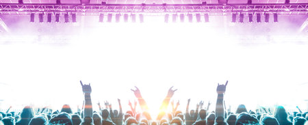 Music festival shot inside a concert hall with people clapping a band on the stage for a live show.