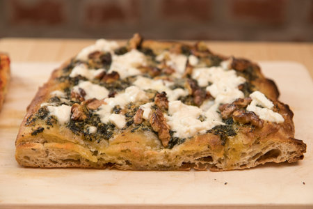 Close up on italian pinsa, a kind of pizza, resting on a restaurant table top.