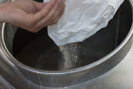 Detail of pouring beer malt into an industrial boiler, inside a brewery. Malt is blurred because of...