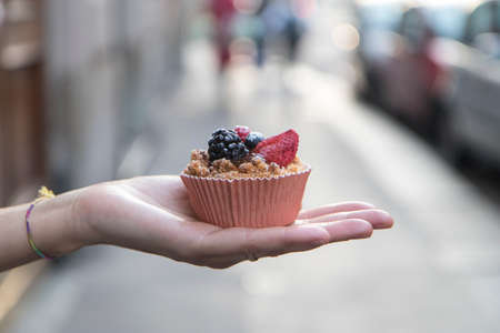 Close up on hands giving a cupcake towards the camera.の写真素材