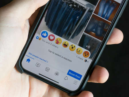 Milan, Italy - June 28, 2020: close up on a modern smarphone screen, newly introduced Facebook post reactions are visible on screen.のeditorial素材