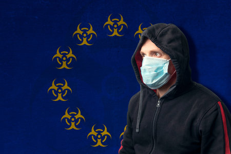 Portrait of a hooded man wearing a surgical respiratory mask against COVID-19 coronavirus,...