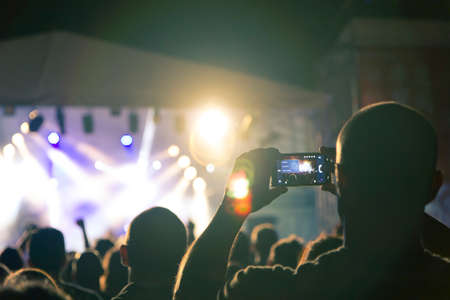 Concert crowd point of view in front of a lit stage for a night festivalの写真素材