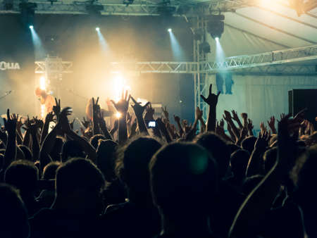 Concert crowd point of view in front of a lit stage for a night festivalの写真素材