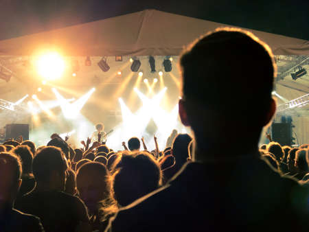 Concert crowd point of view in front of a lit stage for a night festivalの写真素材
