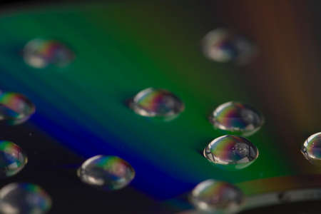 Macro shot of water drops on a CD surface for an abstract background.の写真素材