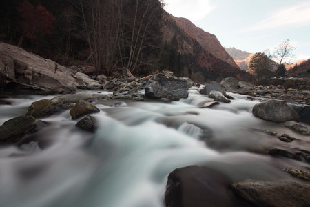 Long exposition shot of a river with silk effect on the water, while the rocks and background are...