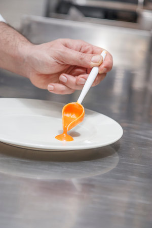 Close-up Of Chef's Hand Cleaning Dish With Spoon In Kitchen