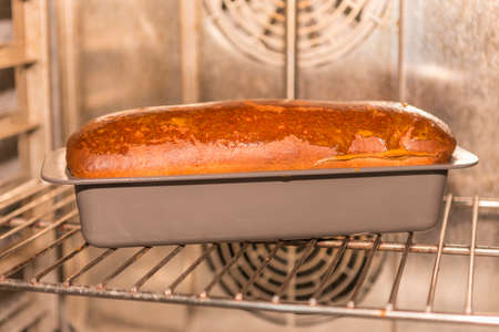Freshly baked loaf of bread in a baking dish on a baking sheet.の写真素材