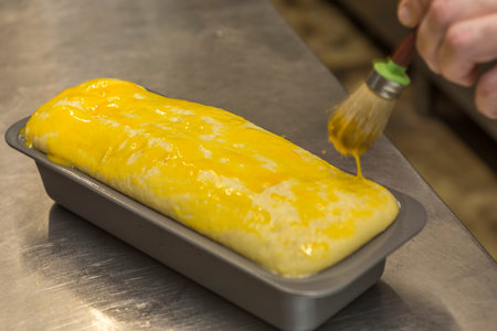 Chef making crepes on a metal tray with a brush.