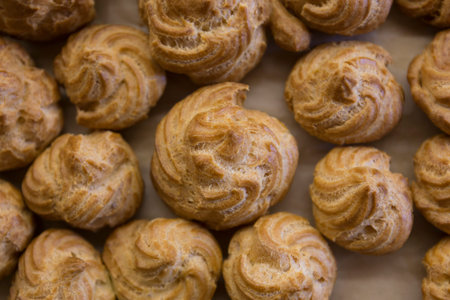 Cream puff pastry with custard cream on a baking paper.の写真素材