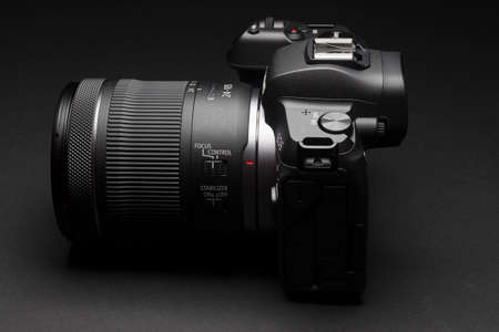 Milan, Italy - January 1, 2022: close up on Canon EOS R mirrorless camera resting on a black background and shot with light painting, no people are visible.のeditorial素材
