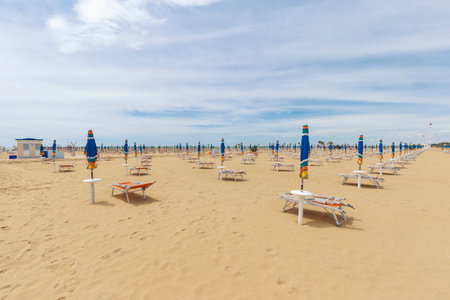 Daylight landscape of an empty beach, sun umbrellas and benches are visible but there are no people.の写真素材