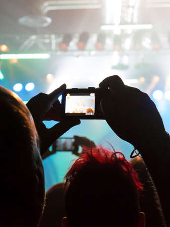 Concert spectators in front of a bright stage with live musicの写真素材