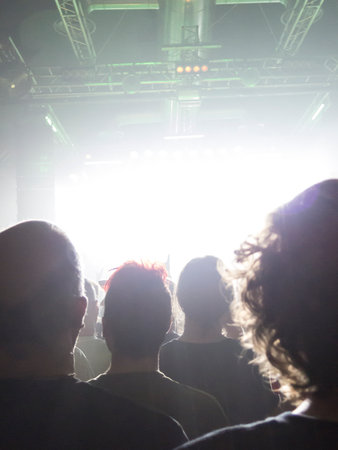 Concert spectators in front of a bright stage with live musicの写真素材