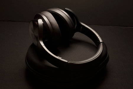 Modern wireless headphones with travel bag resting on black background.