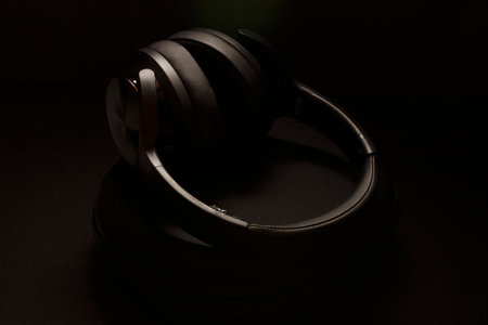 Modern wireless headphones with travel bag resting on black background.