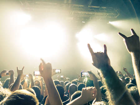 Crowd at a concert in front of a bright stage lighting.の写真素材