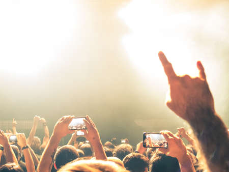 Crowd of people at a live music concert taking a selfie with a smartphoneの写真素材