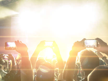 Silhouettes of a concert crowd in front of bright stage lightsの写真素材