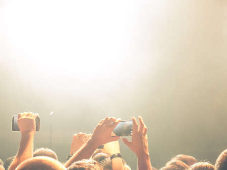 Crowd of people at a live concert with hands raised up.の写真素材